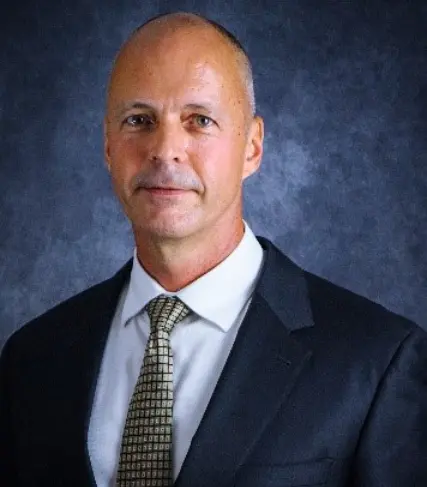 A man in suit and tie standing next to wall.