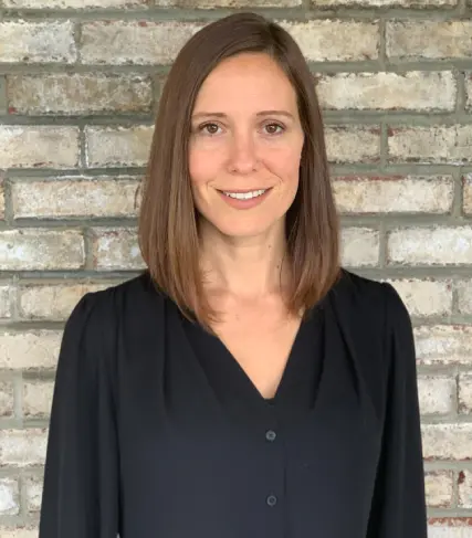 A woman standing in front of a brick wall.