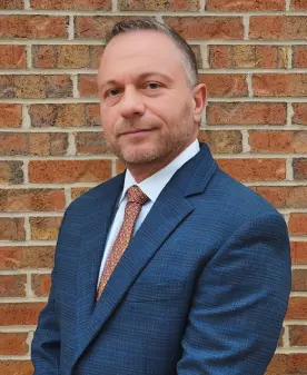 Man in a suit and tie, smiling.