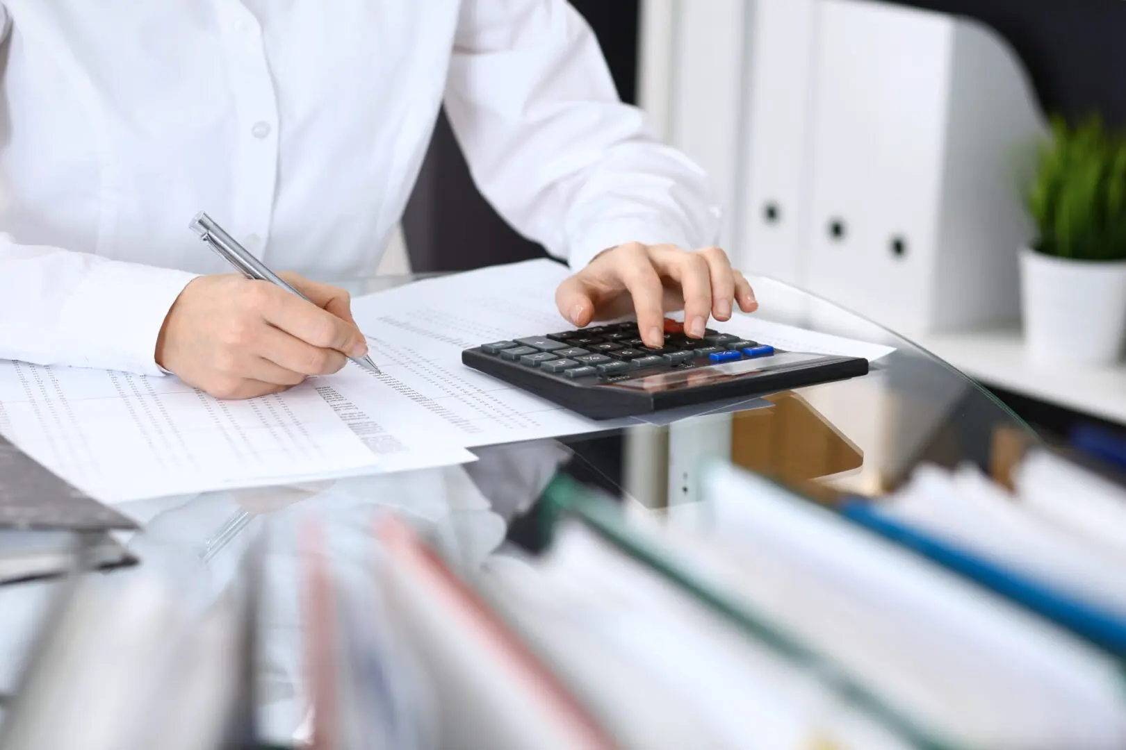 Close up of someone's hands on a desk reviewing costs with a calculator