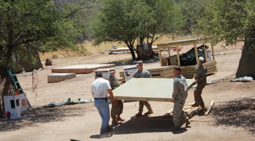 A group of men carrying furniture on top of a dirt road.