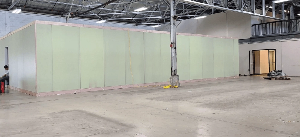 A large warehouse with green walls and concrete floors.