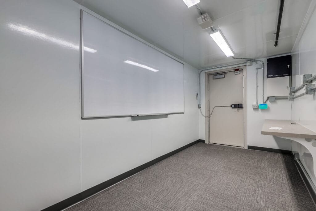 The inside of a container SCIF with a whiteboard on the wall